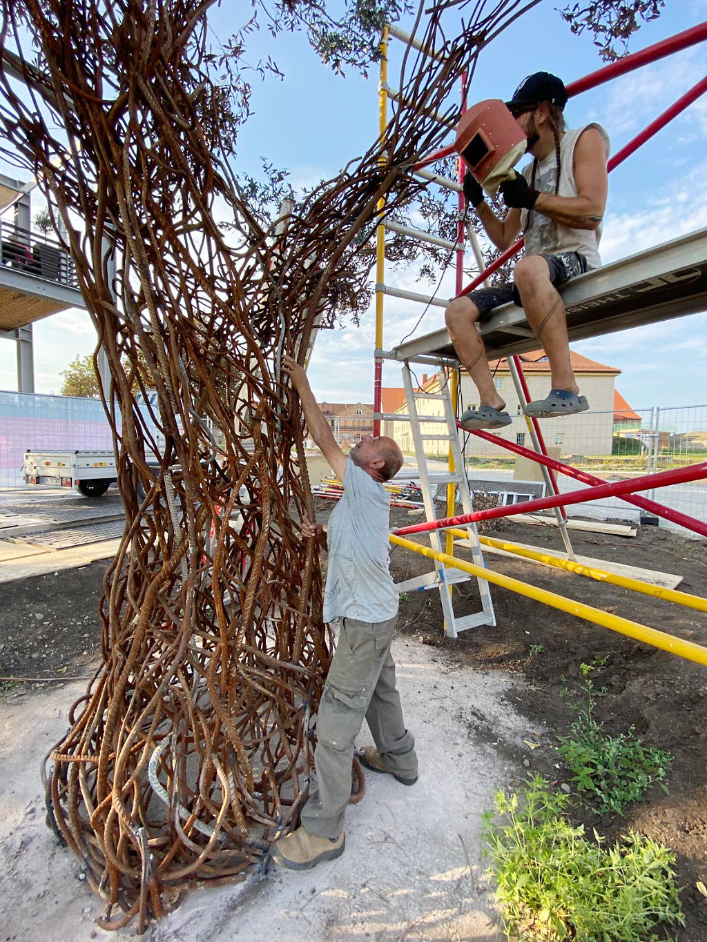 Die Künstler Nihad Dabeet (Ramle, Israel) und Dr. Molrok (Erfurt, Deutschland) schweißen gemeinsam einen Ast an den Paradiesbaum. (© ACHAVA e. V.)